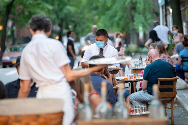 Masked waiters serve outdoor diners during the coronavirus pandemic.